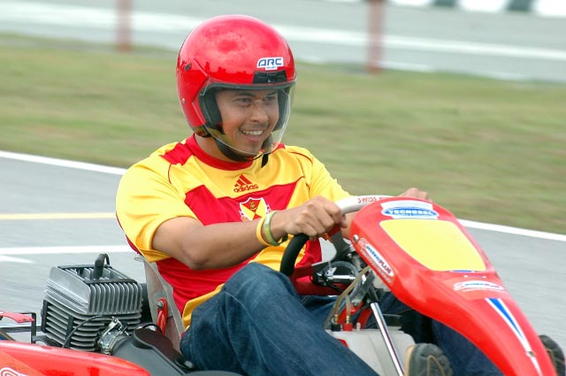a smiling man riding a small red and yellow vehicle