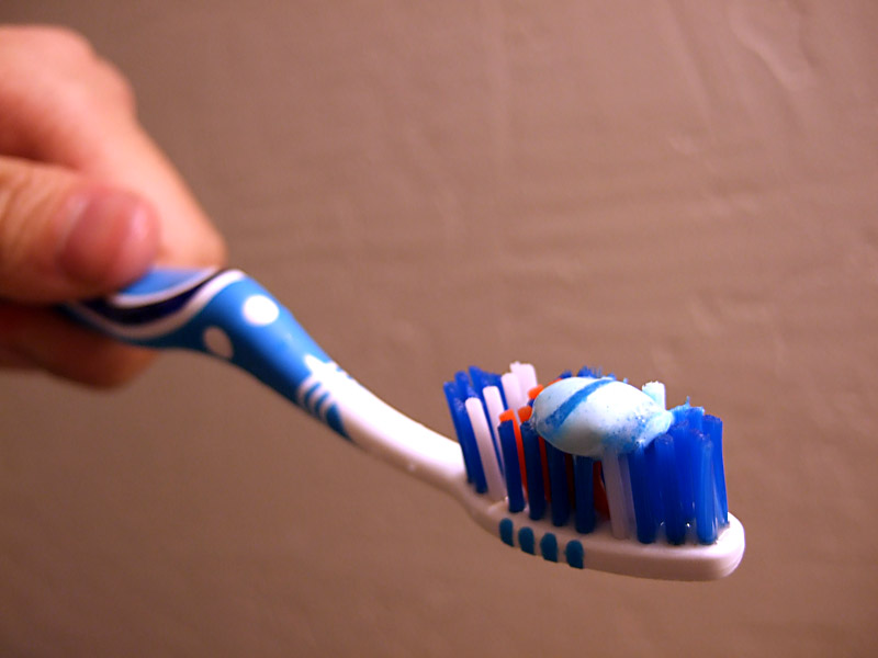 a person holding up a blue and white toothbrush