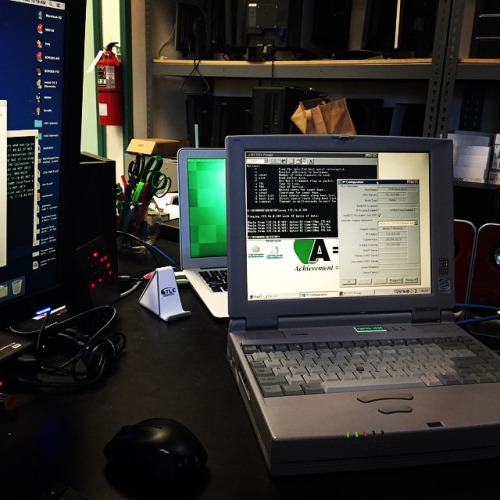 three laptops sitting on a desk in a cluttered room