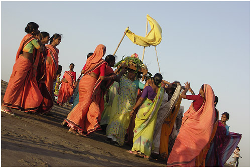 group of indian women in sari walking along beach