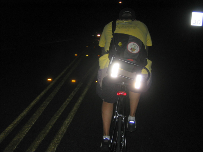 a man on his bike at night with the light on and one hand in the front