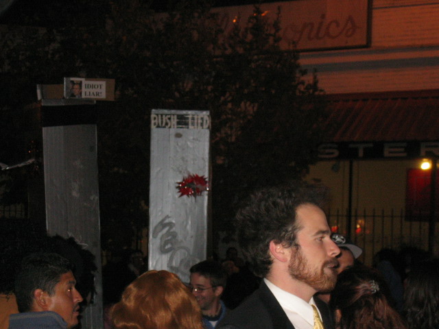 a man in a black suit is standing outside
