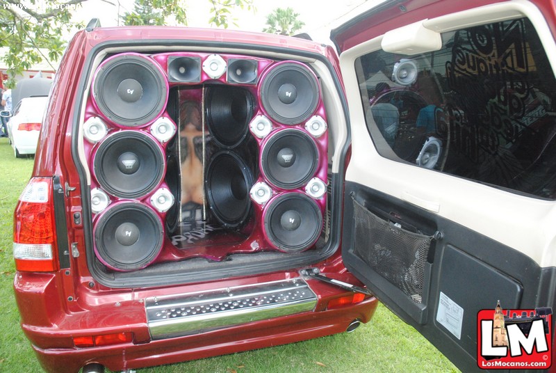 the back end of a red car is loaded with speakers