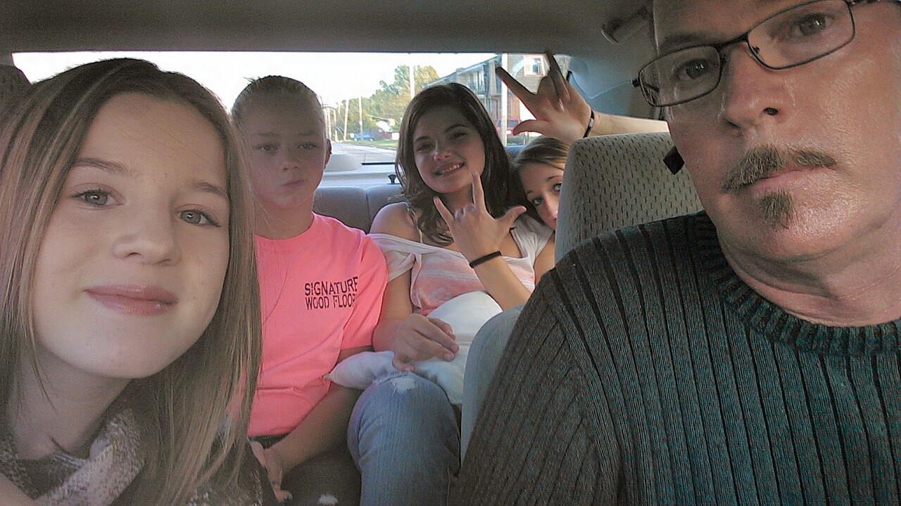 several people sit in the back of a car, both smiling and making silly faces