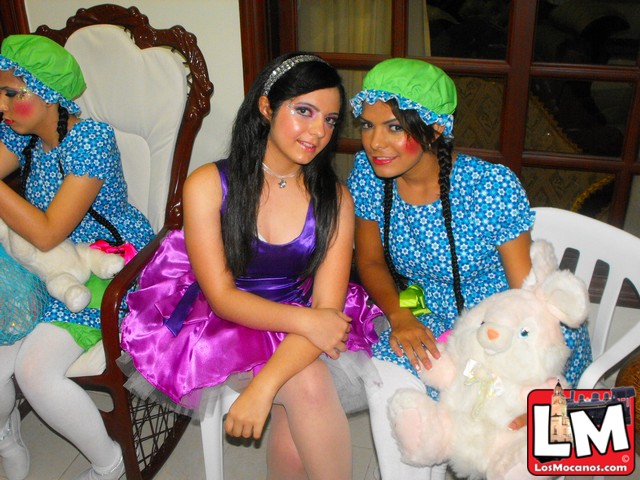 three women sitting in chairs, one dressed as a girl with green hair and the other in purple