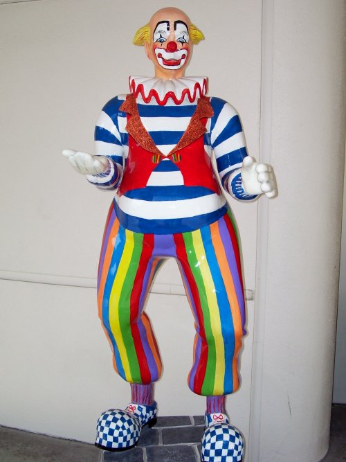 a clown statue is displayed outside in a courtyard