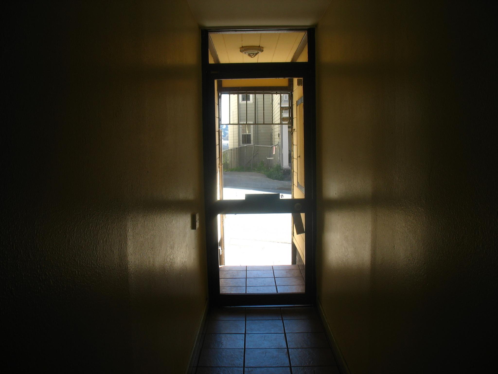 an open door in a dark hallway with white tile