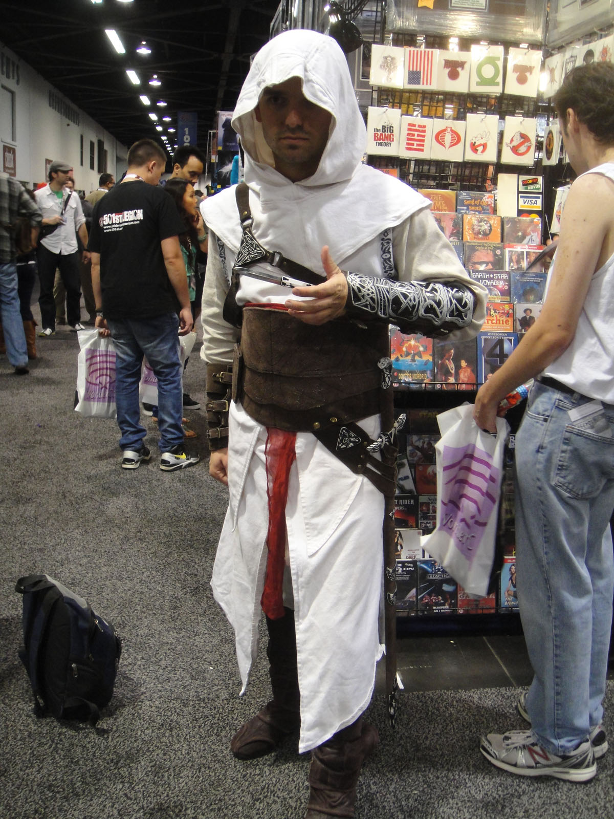 a man in white hoody and long robe holding up some items