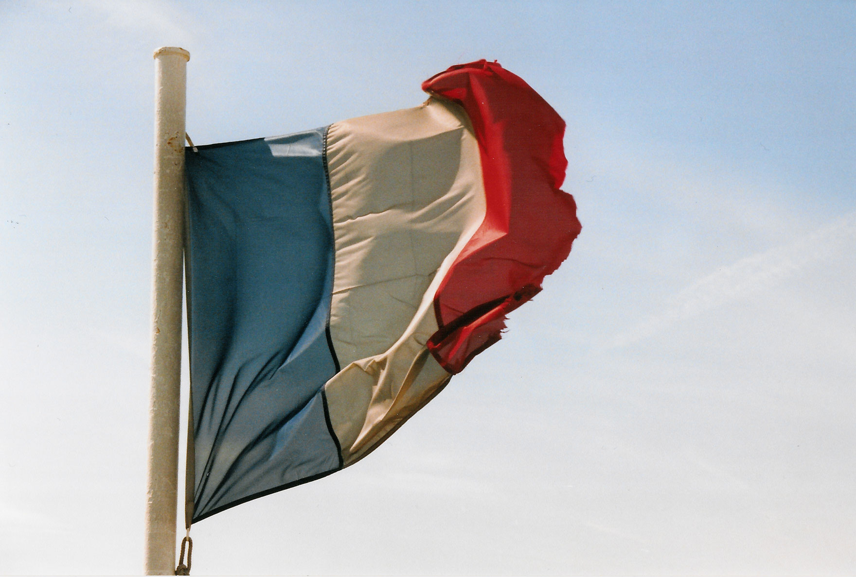 a brown, black and red flag waving against the blue sky