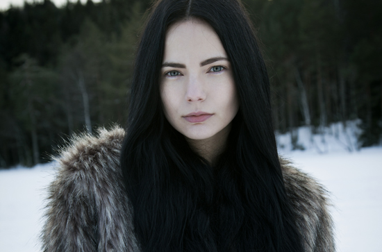 a woman with black hair and fur collar posing