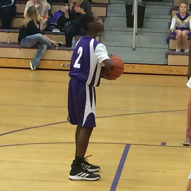 a man holding a basketball on top of a gym floor