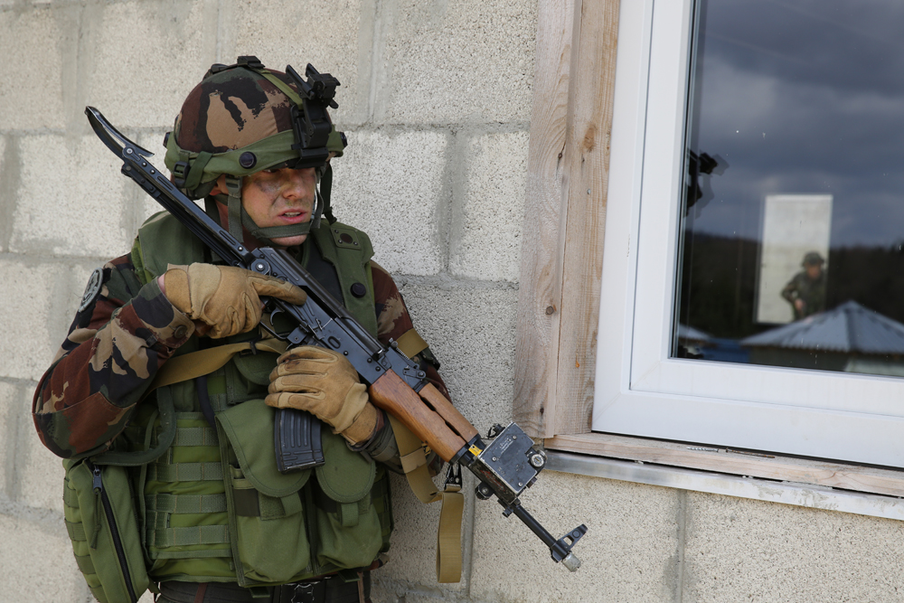 a soldier is holding a gun and another in camouflage