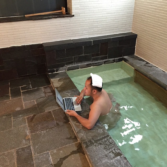a man sitting in an indoor swimming pool holding a laptop