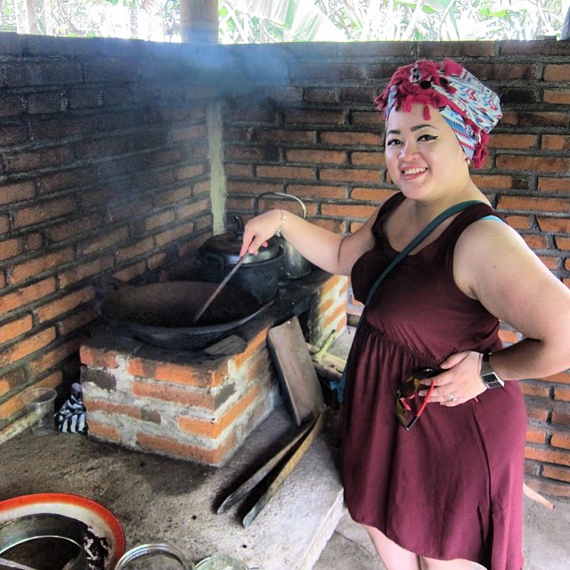 a woman wearing a dress and a headwrap cooking