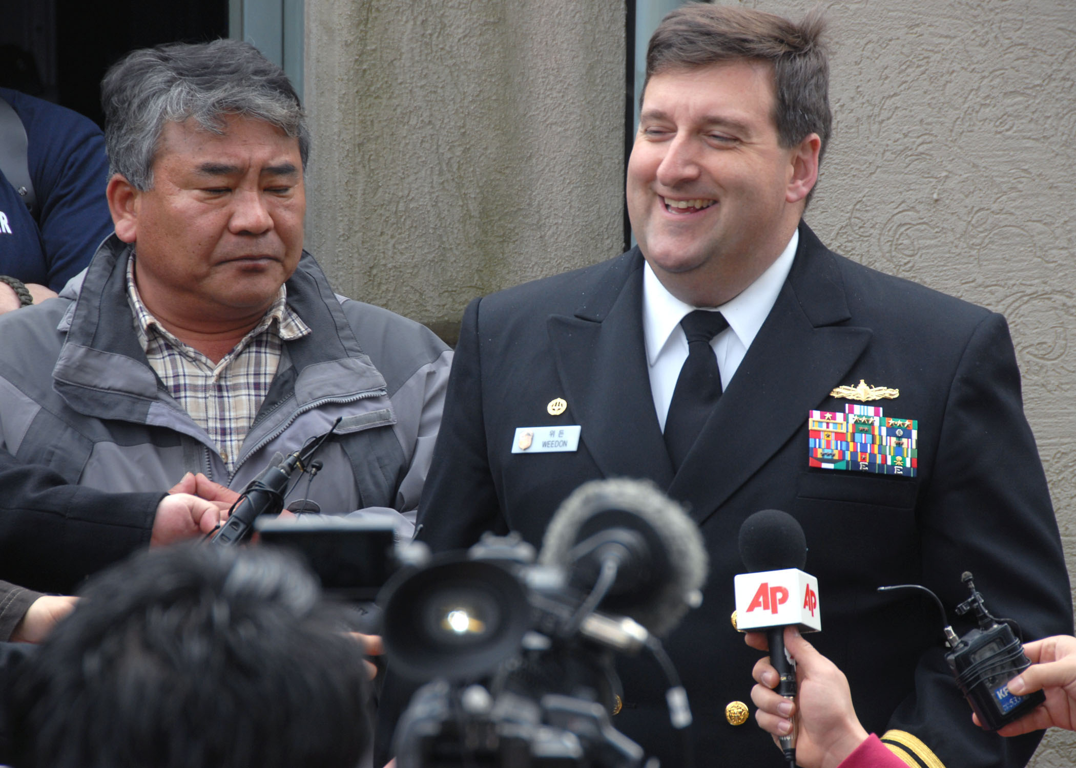 a man in uniform is surrounded by reporters