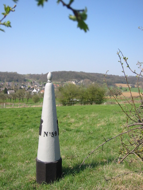 a small triangle marker in the grass in front of a town