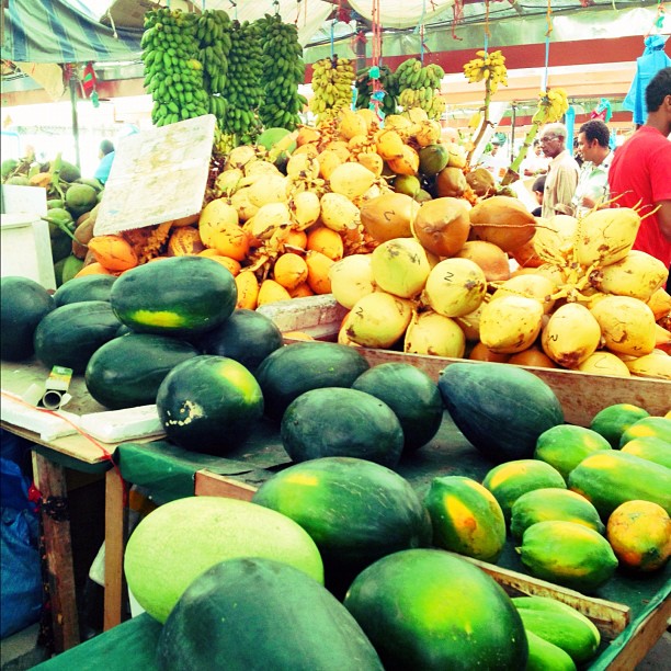 a man is standing in front of an assortment of fruit at a market