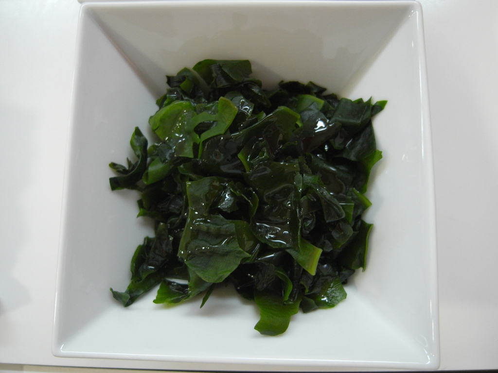 a square white dish with green leaves inside