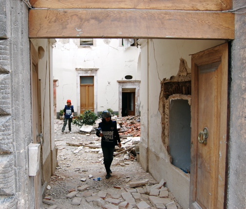 two people walking through an alleyway in a town