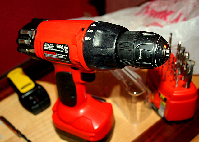 a drill and tools are sitting on a wooden counter