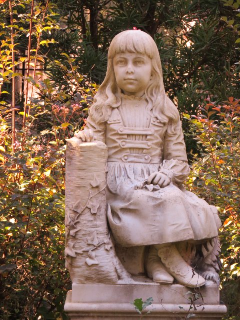 a statue of a girl sitting on top of a bench