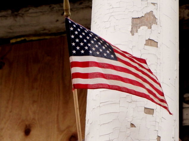 a small flag on a white pole and some wood