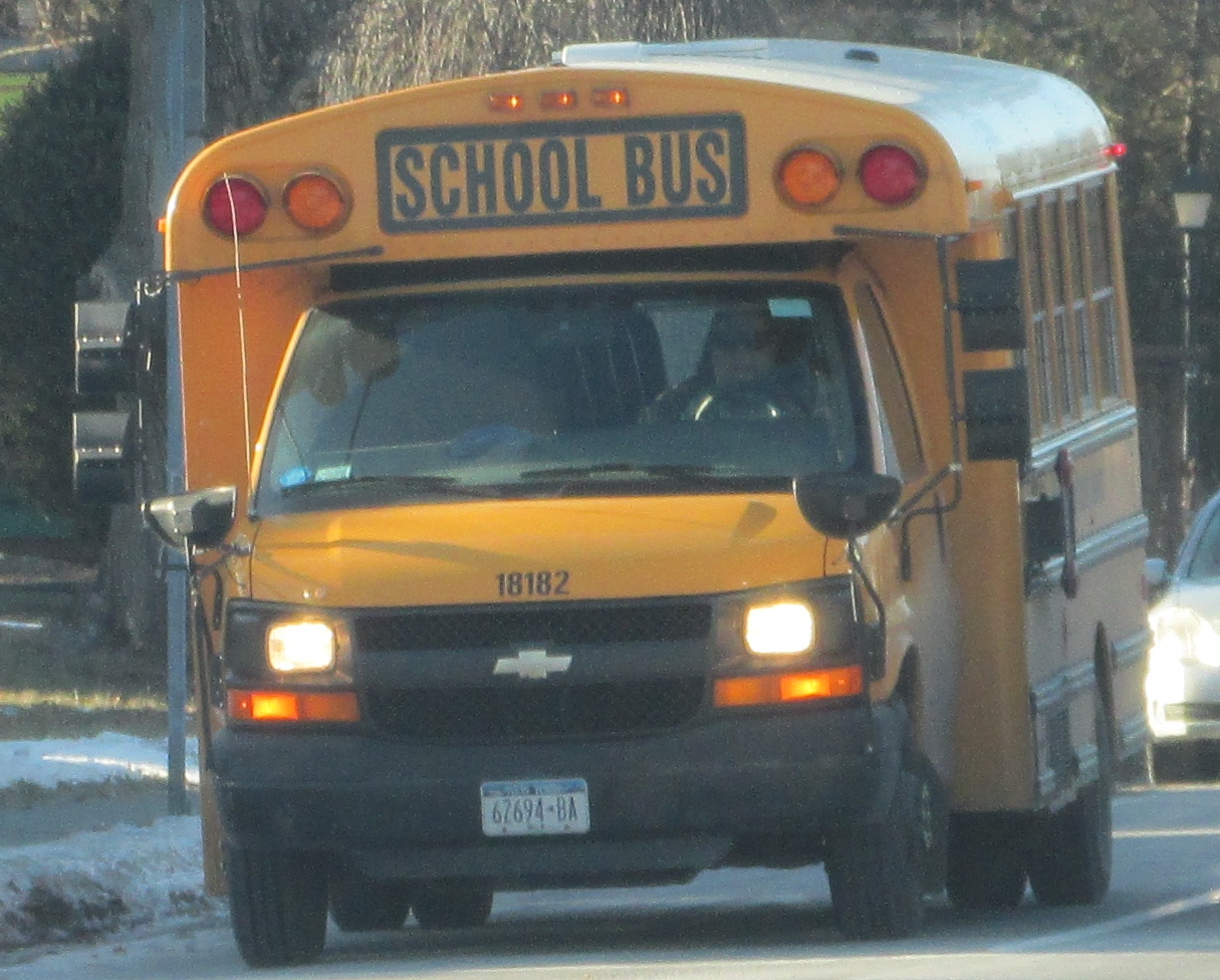 a yellow school bus driving through traffic on a snowy road