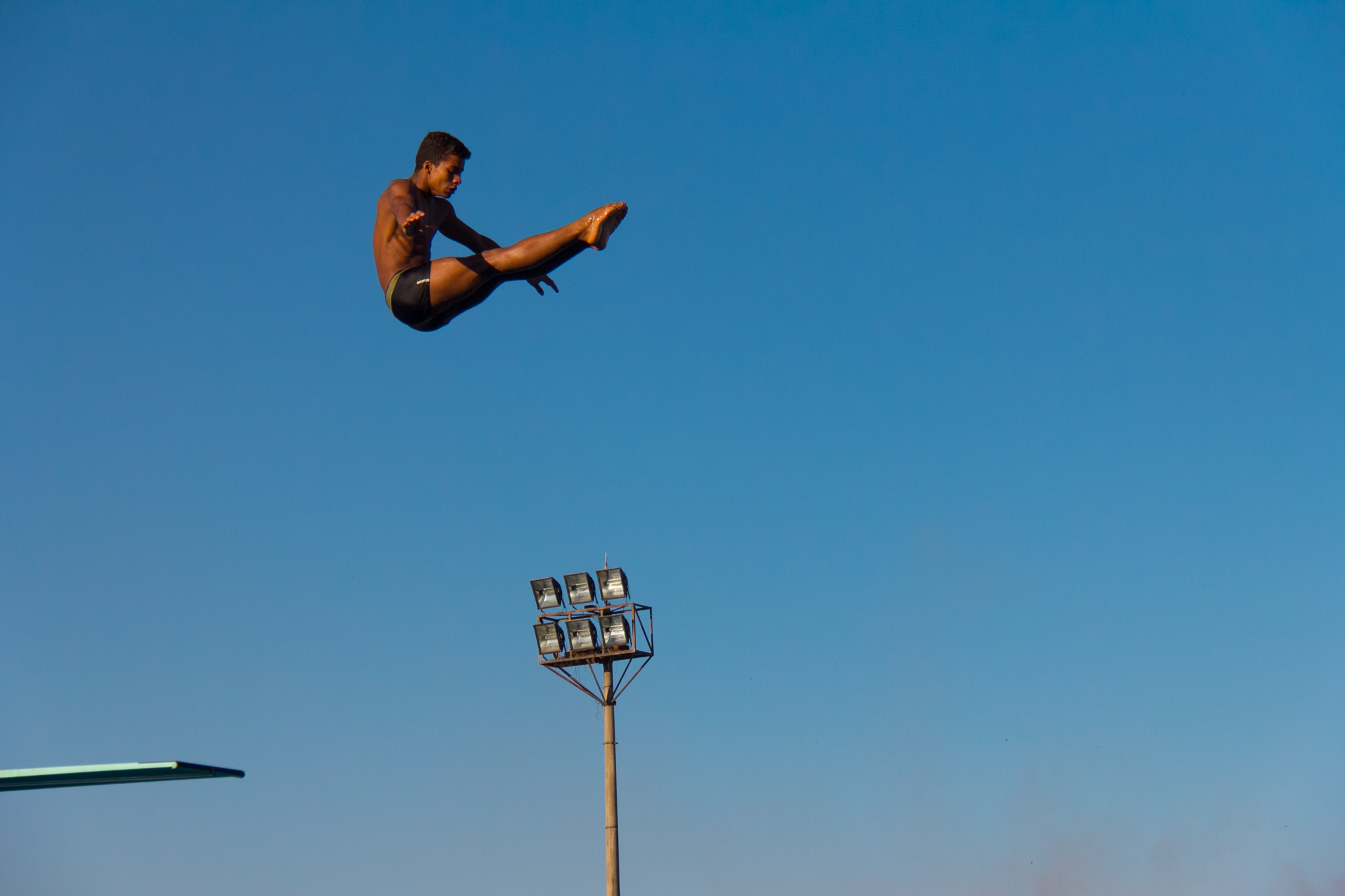 a man jumping in the air while holding onto a blue umbrella