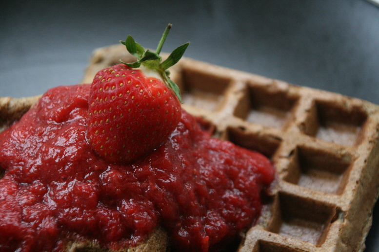 a strawberry on top of some waffles with syrup