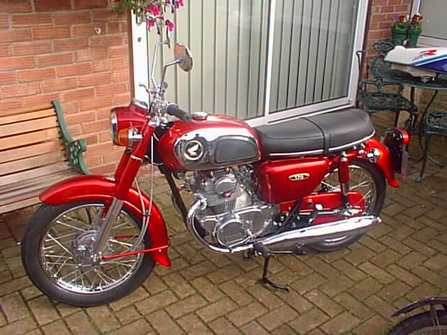 an antique red motorcycle is parked outside on the brick floor