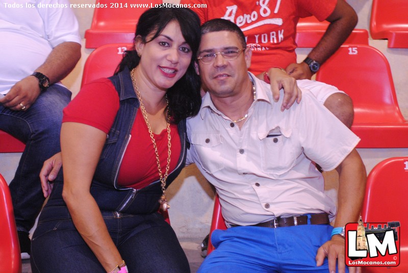 a woman sitting on top of a red chair with a man