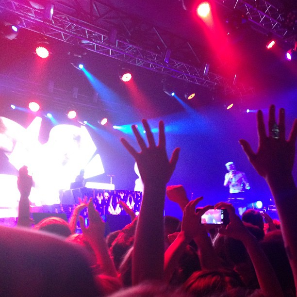 a group of people at a concert with their hands in the air