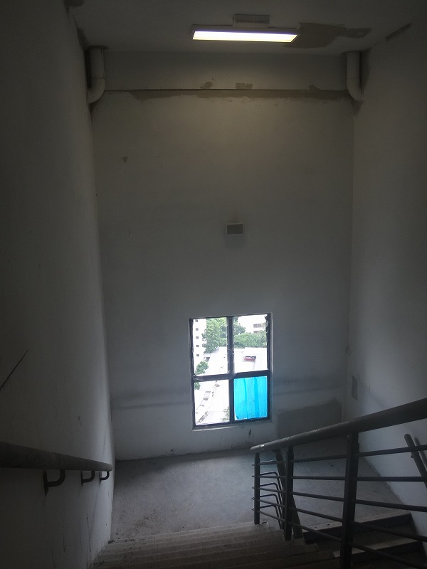 looking down a stairwell towards a bright blue window