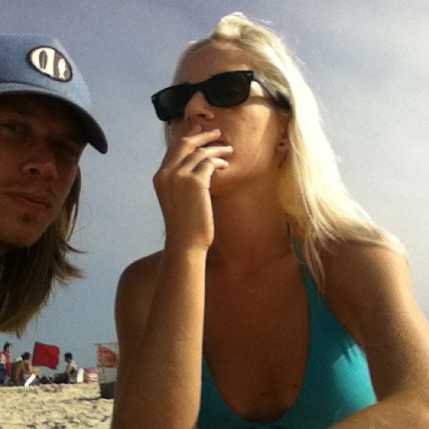 a man and woman on a beach wearing a blue hat