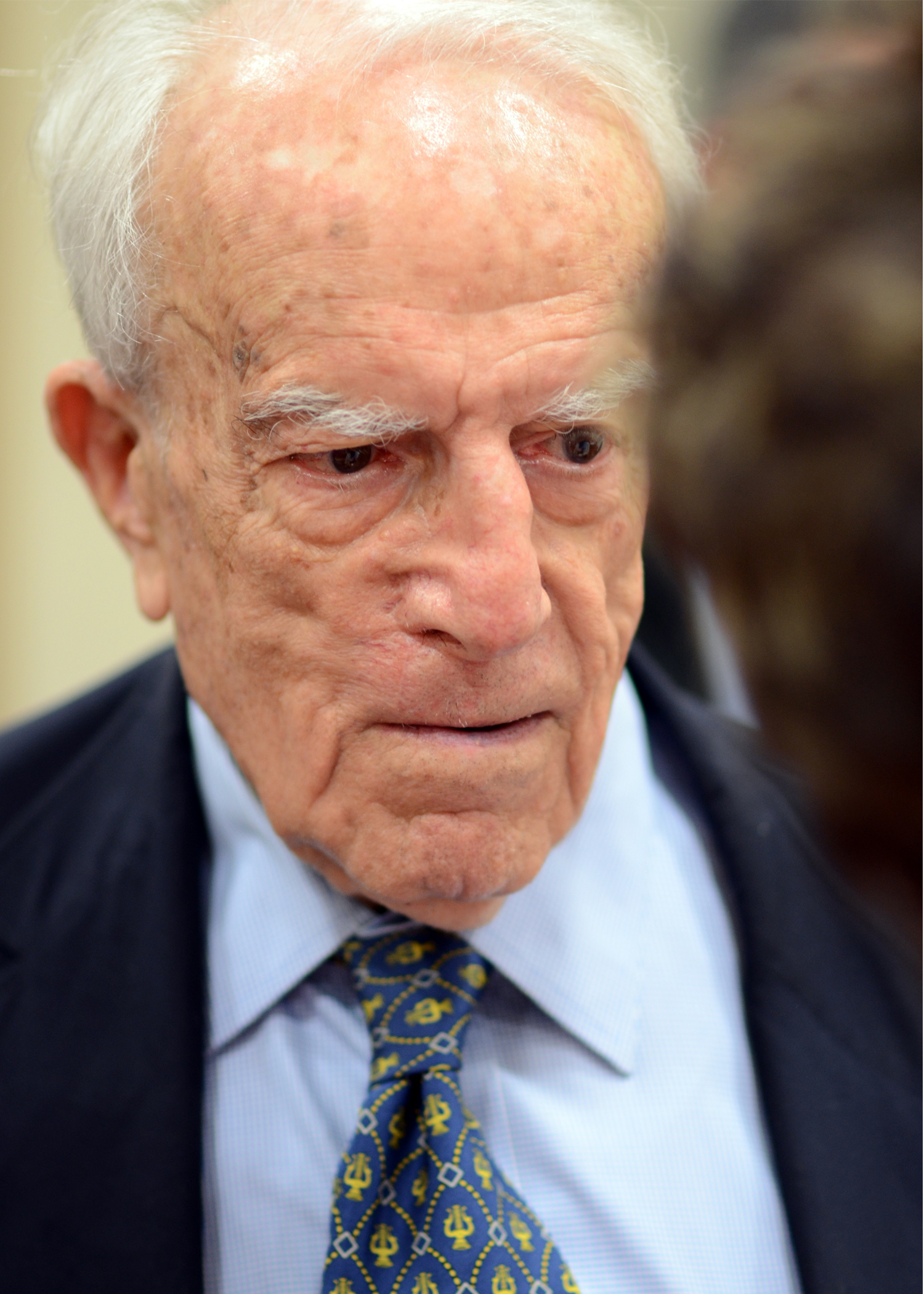 an old gentleman wearing a blue neck tie and a suit