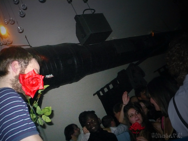 a man holding a fake rose with people in the background