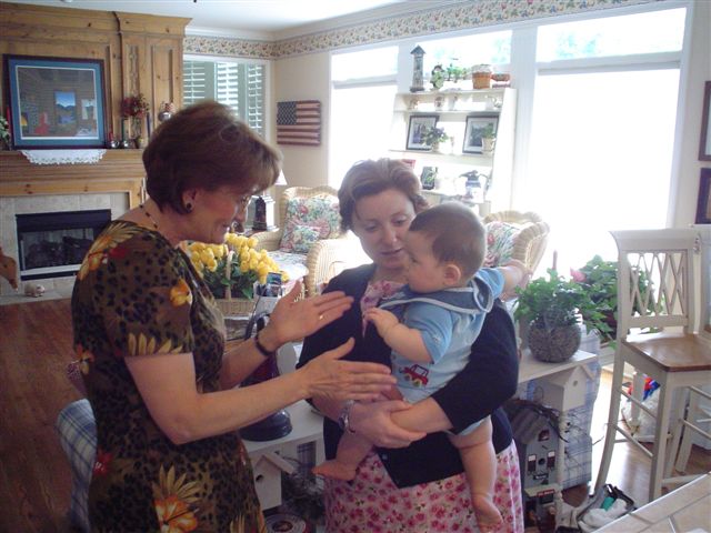 an adult and two small children stand in the kitchen while the woman holds the child up