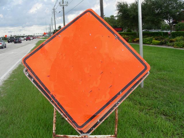 an orange street sign sits in the grass