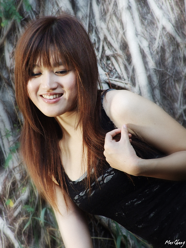 a woman with red hair and black shirt posing by a tree