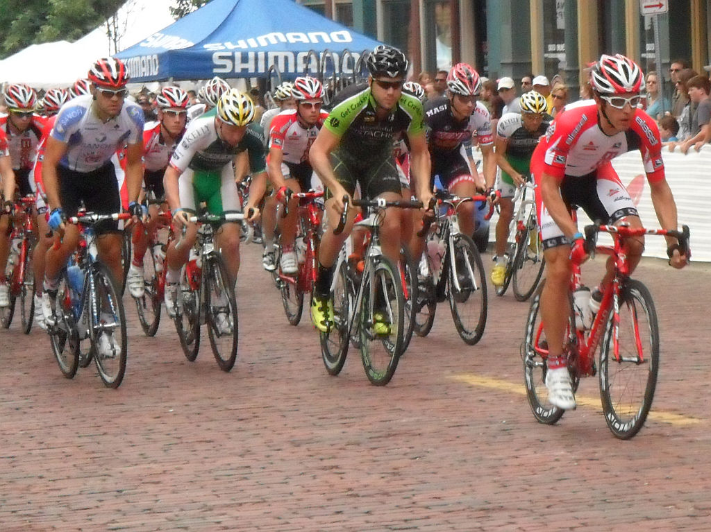 a bunch of bicyclists in the street in front of a tent