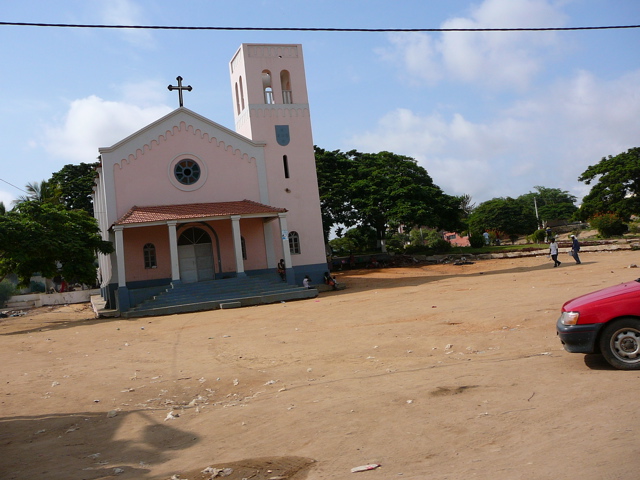an old church sitting next to some people on a road
