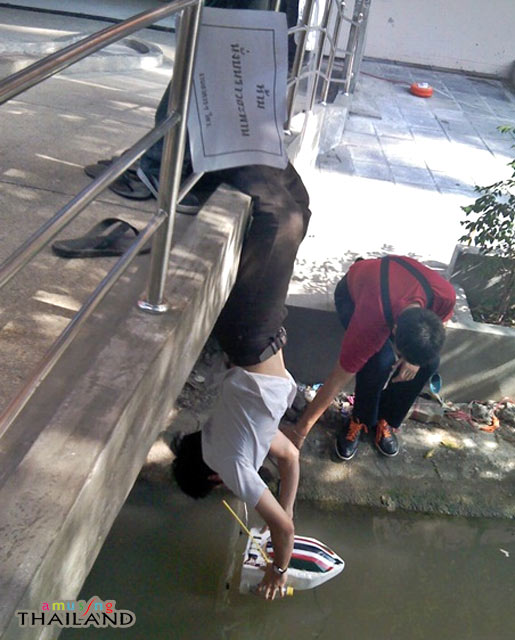 a person holding a bucket in the water near a skateboard