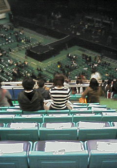 people sitting at a tennis court with a crowd of onlookers