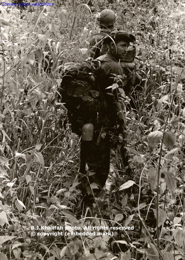 two men are hiking in a field of tall grass