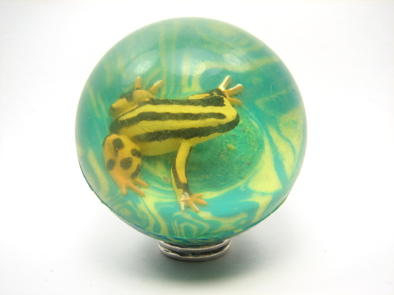 a frog sits on a green glass ball