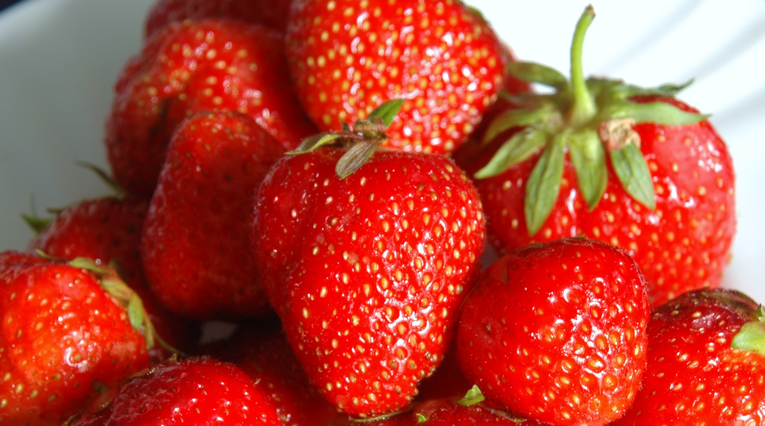 a large group of fresh strawberries in a white bowl