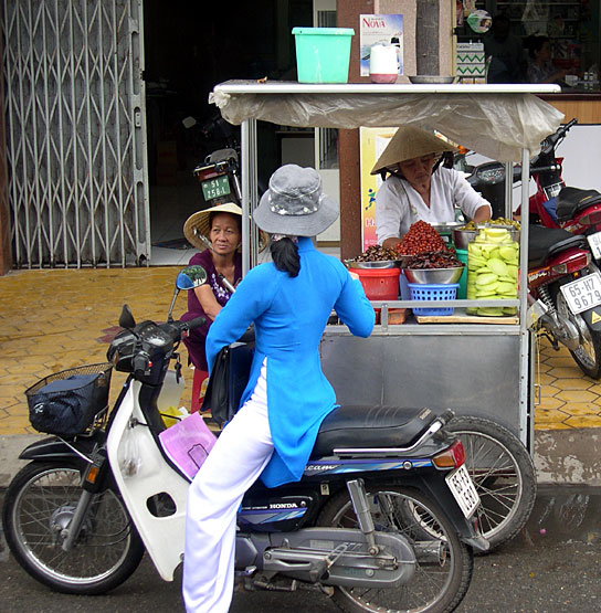 some women and children on some motorcycles by some food cart