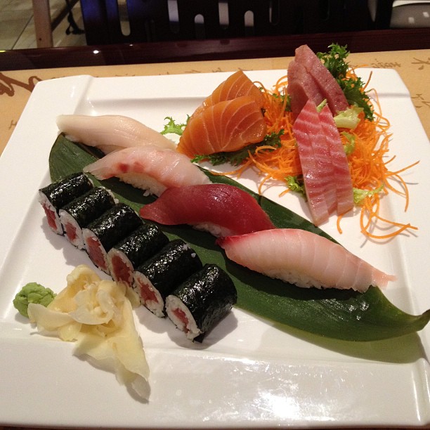 two sushi dishes on a plate, with one large green leaf and two small sections of meats