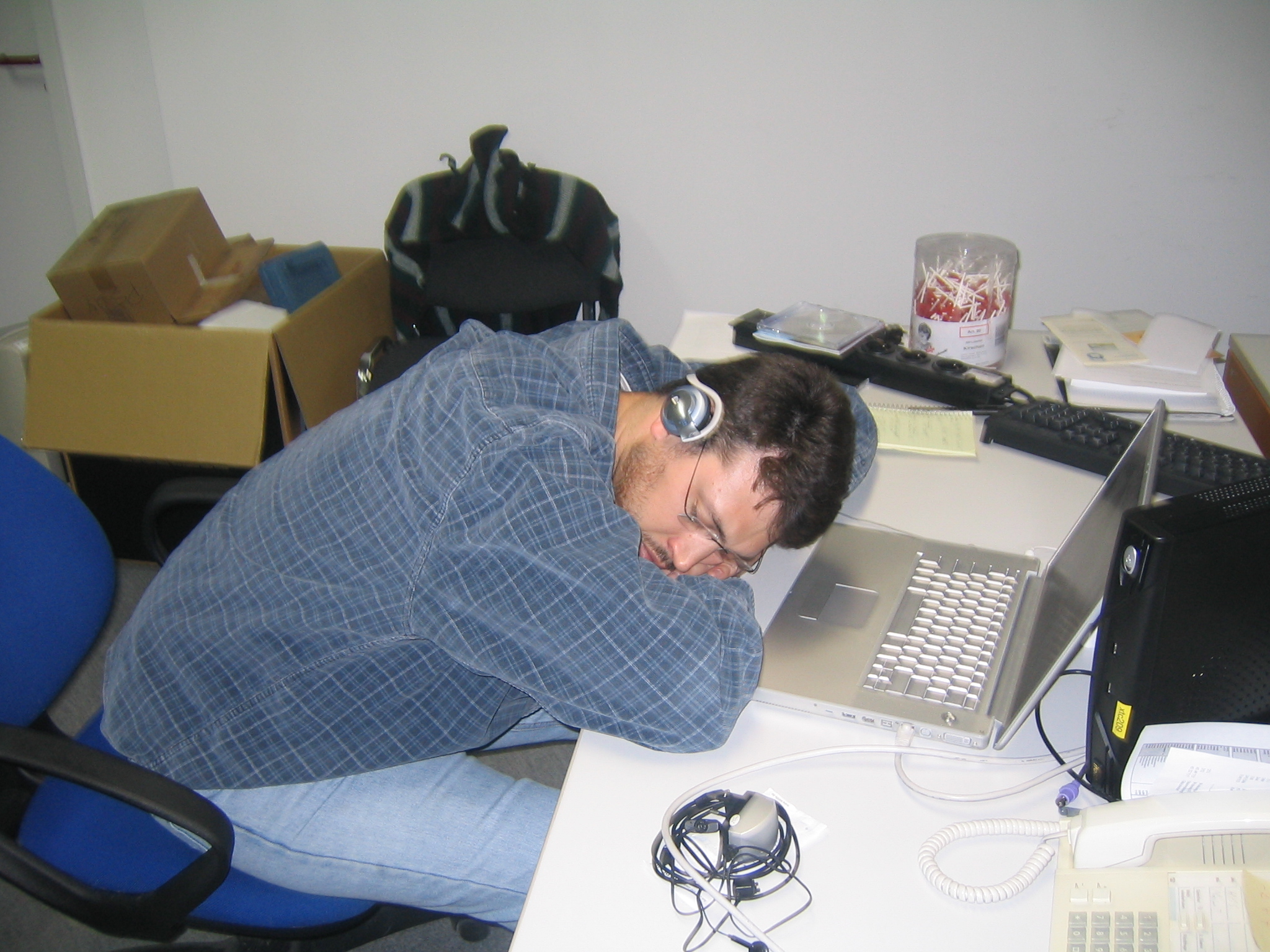 a man in headphones laying his head on a desk