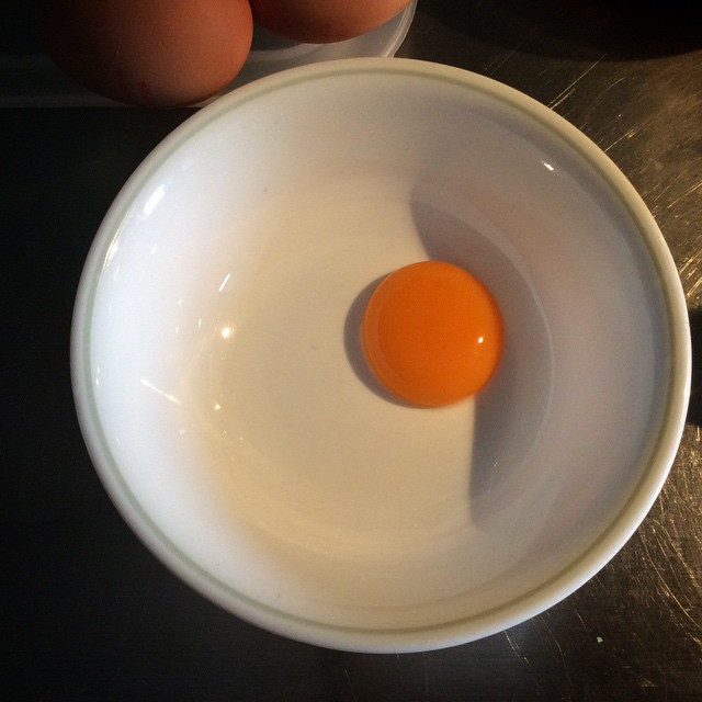 two orange eggs sitting inside of a bowl on a table